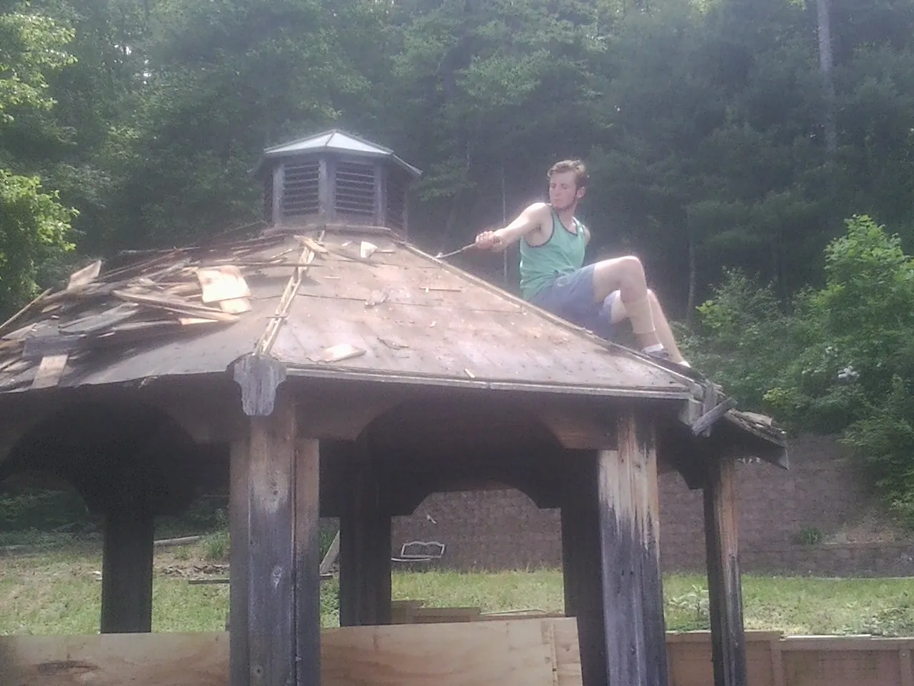 Tearing the old roof off a wooden gazebo before new shakes in Sedgwick