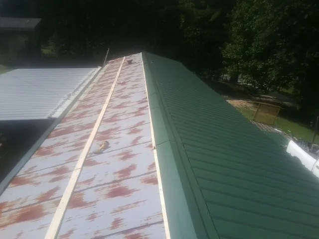 Old rusted panels beside newly installed green metal roofing — Wind Damage Roof Repair by Roofing Brothers in Sedgwick
