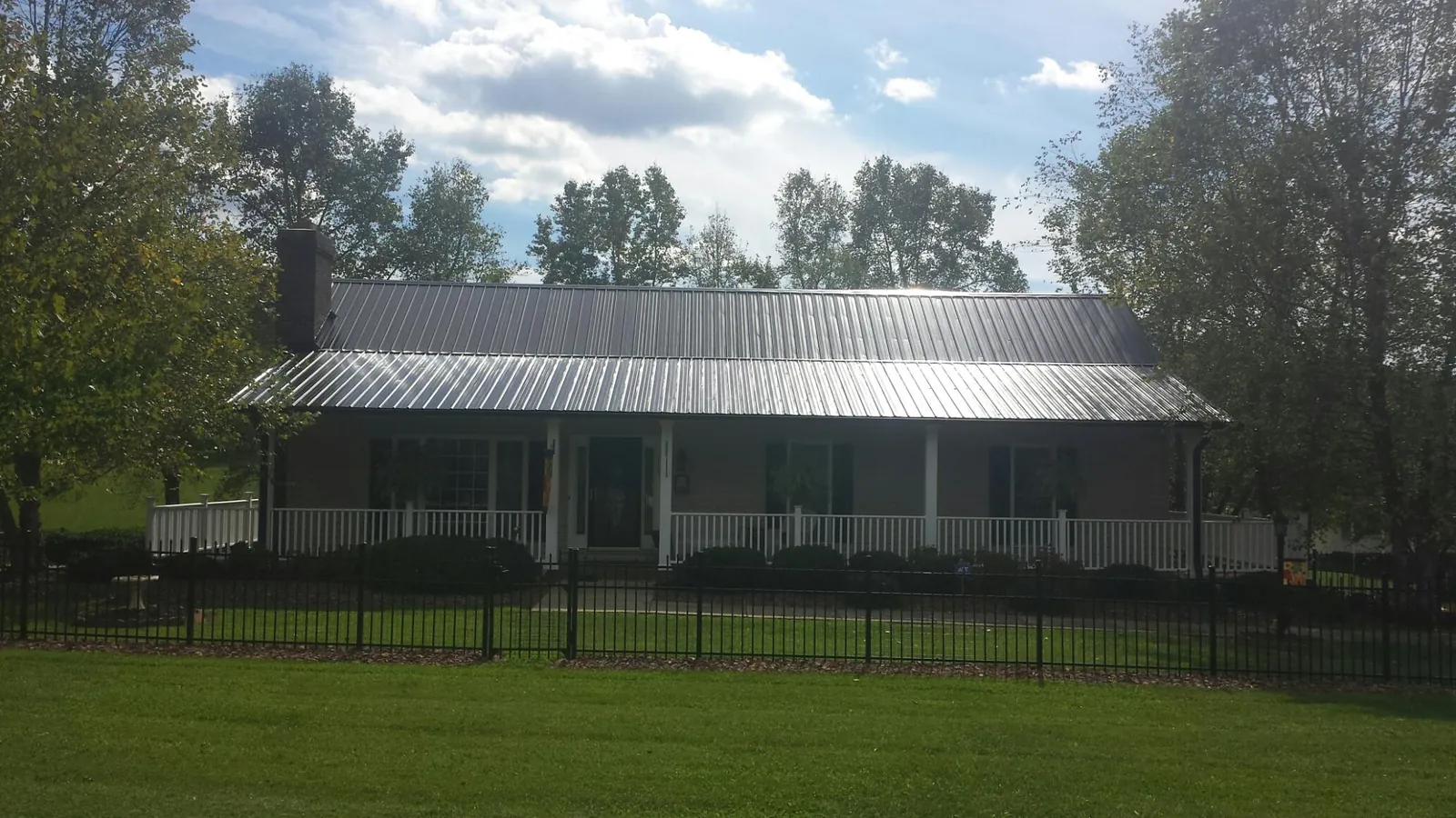 Gray metal roof on a brick ranch with a full width front porch — Gutter Guard Installation work by our crew in Sedgwick