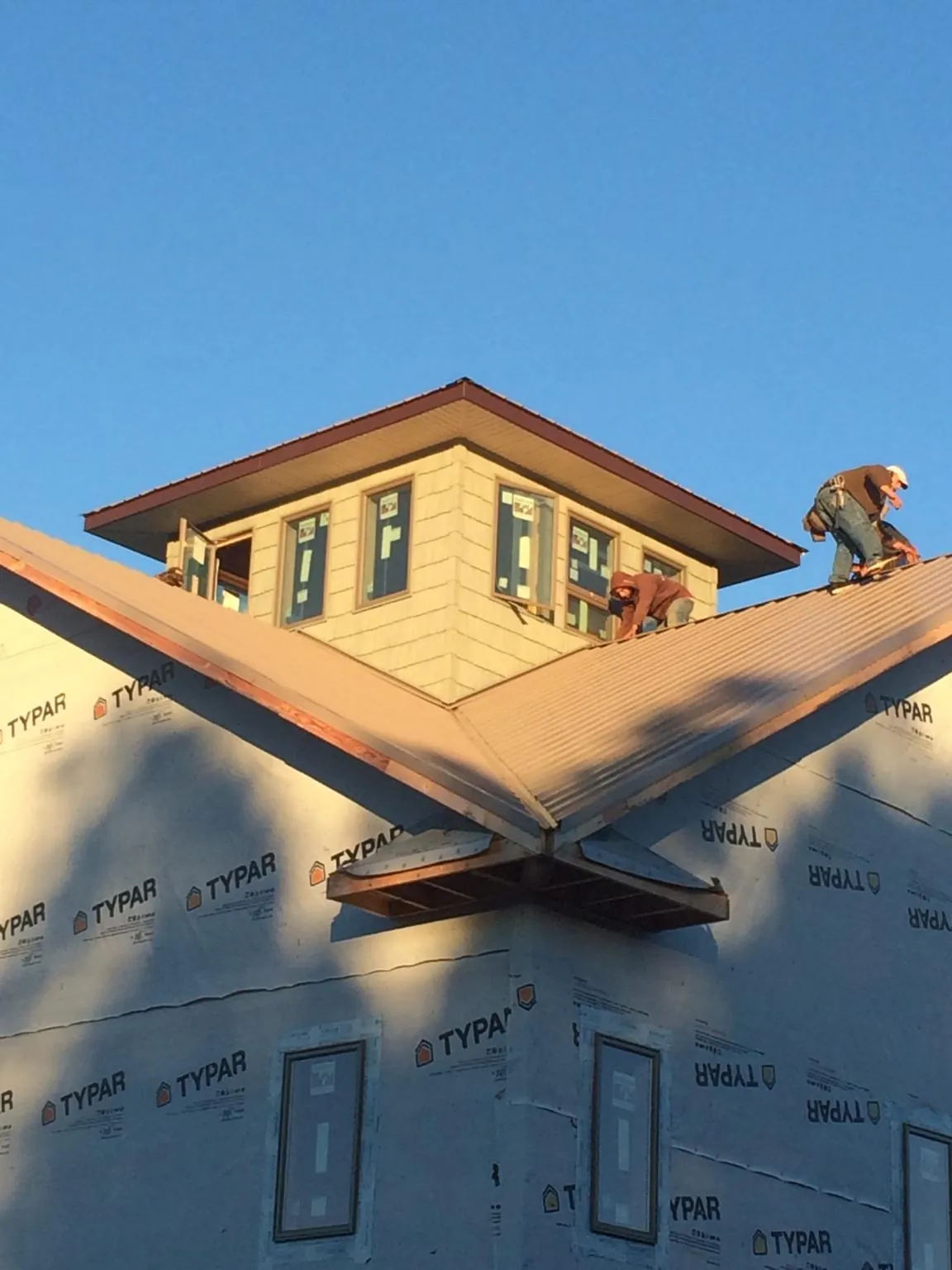 Roofers working around a rooftop cupola on a new metal roof at sunset — Roof Waterproofing in Sedgwick by Roofing Brothers